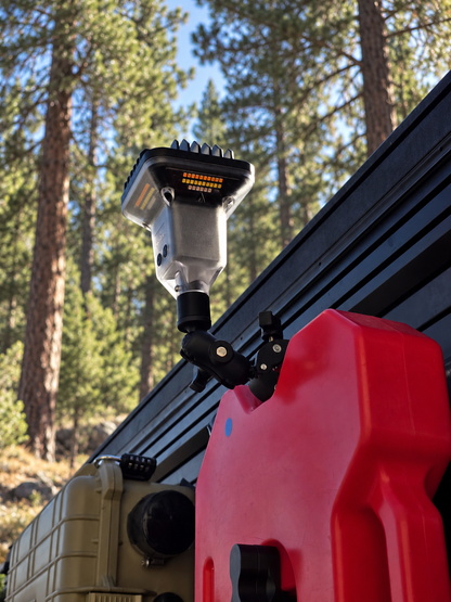 FireCrateUSA SuperClamp holding a Devos LightRanger beside a red recovery board at a pine forest campsite